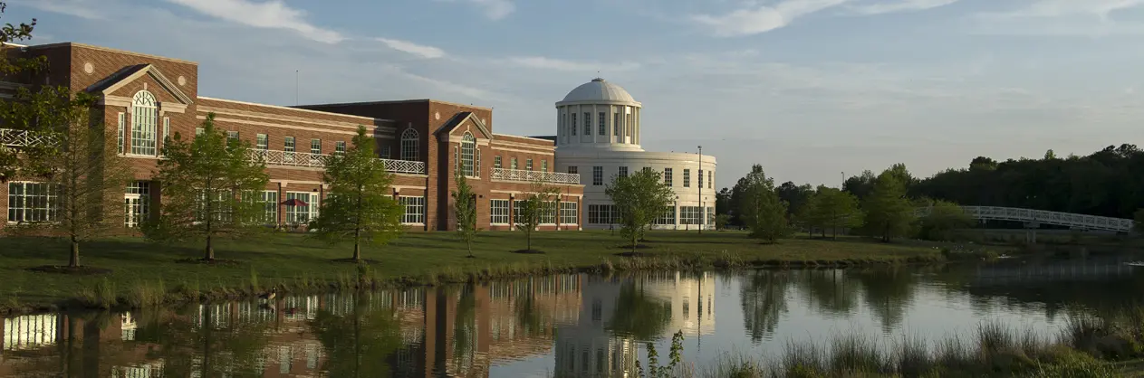 Massachusetts Institute of Technology’s iconic main building features grand columns and a central dome, framed by bare trees in a serene setting.